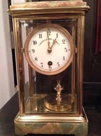 A Claude Grivolas 400-day
Torison-style mantle clock with
a white porcelain face with
black, Arabic numerals, brass
minute and hour hands and a
glass case with a marble top
and base. The piece is 11.5
inches high, 6.5 inches wide
and 5.5 inches deep.