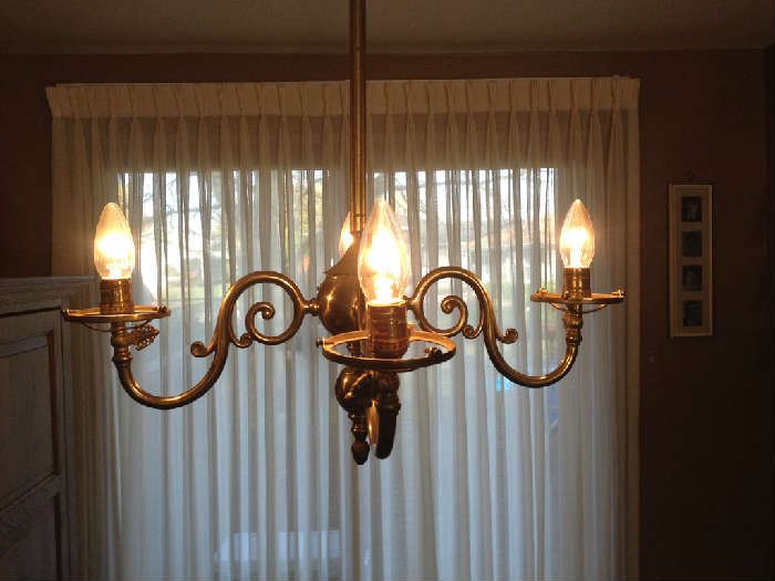 Brass hand forged chandelier with four lights and glass shades.