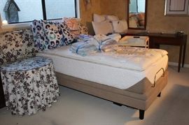Bed with linens, comforters, tables, padded king size headboard.