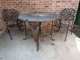 Beautifully patinated wrought iron outdoor table, with stone top. The chairs have been recently refreshed by famed Atlanta faux painting guru, Corey VanCleve.