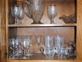 Top Shelf: Iris & Herringbone Pitcher & Stem Glasses and Serving Bowl.  Bottom Shelf:  Tiffin & Rose Point Stem Glasses and Rose Point C & S