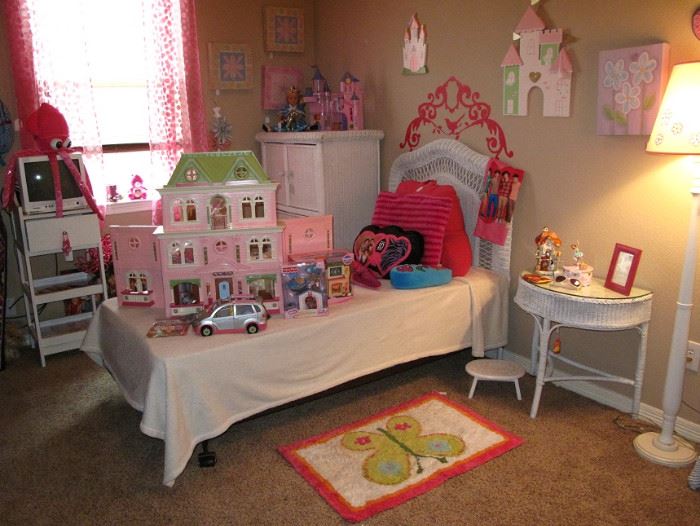 Another view with Various Toys and Doll House!  Twin White Wicker Bedroom Suite: Twin Bed with Headboard, 3-Drawer Chest Armoire and a Demi Lune Table.  Also pictured are various wall Decor and White Wooden Floor Lamp with Pink Shade