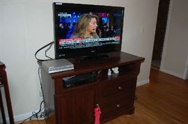 The tv set, the DVD player, VCR and the tv console are all available for purchase.  The wood is a very nice cherry finish and has a larger cabinet on the left and two drawers on the right, along with a small area for display.  Contemporary with satin nickel hardware.