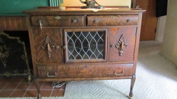 TIGER OAK VICTORIAN CLAW FOOT BUFFET WITH LEADED GLASS DOOR AND RASS PULLS. (GLASS NEEDS REPAIR)