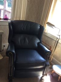 1 of 2 Navy ball and claw foot wing back recliners, also pictured brass floor reading lamp, step stool and magazine rack, purple elephant glass in the window