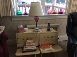 Twin repurposed children school desks, bohemian cut red glass lamp, some examples of colored bottles in the back