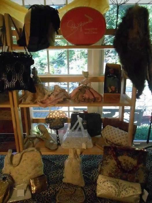 Family Room-SMALLS area:  Displayed are a CIVIL WAR era beaded head covering; an oval SCHIAPARELLI hat box; another fur collar; three porcelain body dolls; one American Indian doll; a pair of Lucite heel shoes; an elegant fan; and several vintage purses, including one Lucite box purse.  A closer photo of some of these items follows.
