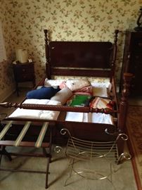 Double bed, no mattress for this suite. Pillows, blankets  and throws stacked here. Also note "brass" wire vanity seat and luggage stand