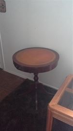 Antique wood table w/leather top, brass hardware, brass caster wheels and has a drawer