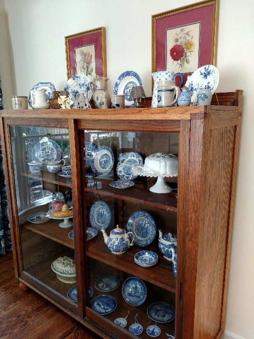 Antique oak two door display cabinet filled with blue and white china by Alpine, Masons, Adams, Buffalo, Willow Ware, Johnson Bros. Staffordshire and milk glass cake plate and compote, etc.