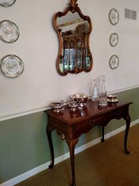 Mahogany console table with gilt mirror above and silverplate serving pieces and crystal decanters