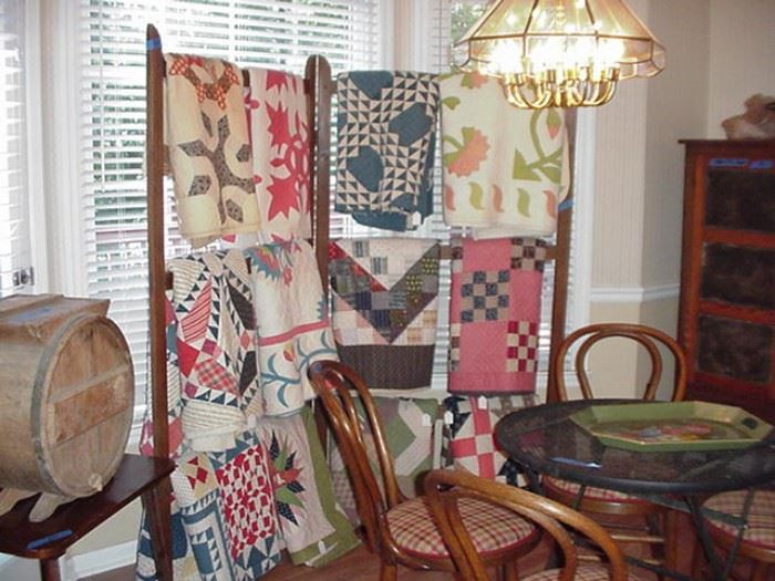 Large collection of 19th C. quilts hanging on antique quilt rack