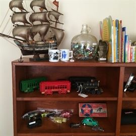 Ship model; Hopalong Cassidy mugs; jug of marbles; children's book; trains, and other toys