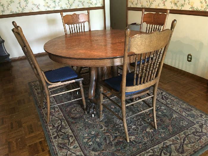 Antique tiger oak table and press back chairs; hidden leaf;  Excellent condition.  Claw foot over wheels.  The area rug is also for sale.
