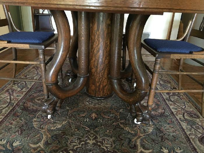 Pedestal and claw foot with cushioned chairs -- antique tiger oak table and chair set.
