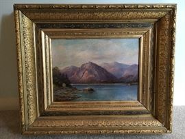 Love this painting. Signed oil painting depicting a placid lake with mountains in the background.