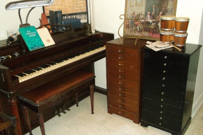 Vintage Wurliter Spinet piano flanked by two music stands and lots of music oriented pieces.