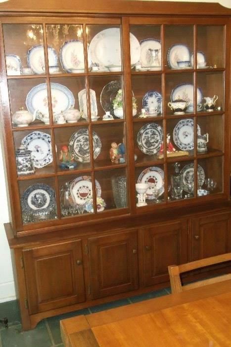 Handcrated china cabinet filled with collections of china and other decorative pieces. Features storage area underneath.