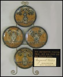  Four ten inch decorator plates with display rack by Raymond Waites