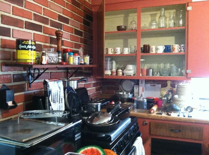 Kitchen items including glassware, pots, pans, wooden rolling pin, Flint utensil set. 