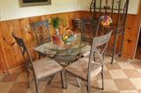 Glass table with four chairs and bakers rack.