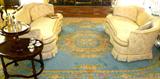 Cream Colored down filled love seats atop a beautiful handwoven rug