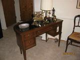 Antique leather-topped round front desk with needlepoint chair.