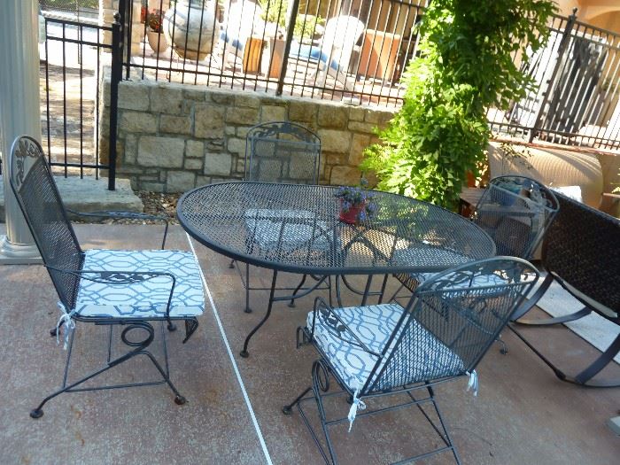 Wrought iron oval table and four rocker chairs with cushions