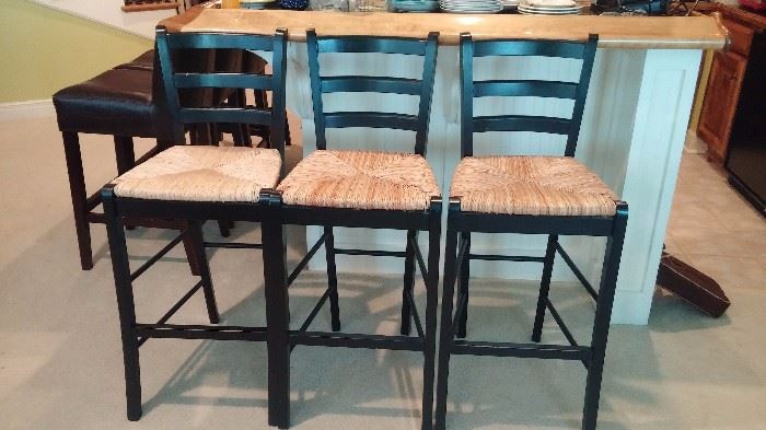 three black cane back and wicker seat bar stools