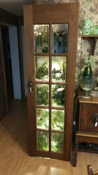 Hand made cabinet with LED lighting made from repurposed doors and beaded board filled with Indiana Green glassware.