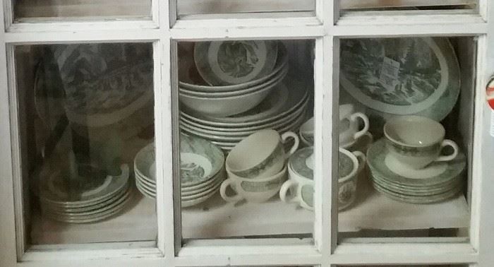 Cream and green dish set. Unmarked. Farm scenes. Dishes are framed with hand plows and horse hanes.