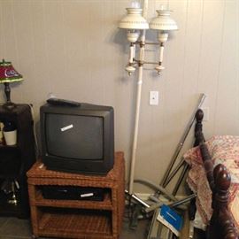 TV, Wicker TV stand, Colonial Pole lamp, and two Electrolux vacuum cleaners