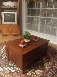 coffee table with drawers, corner entertainment center, television, rug