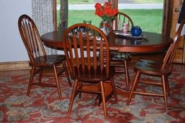 Round oak table with 4 chairs sitting on Pottery Barn wool rug