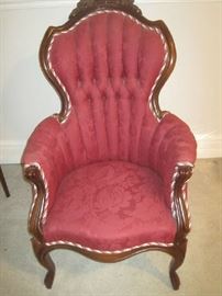 One of two Victorian tufted back chairs with red, white, and green braid trim- Gentleman's chair