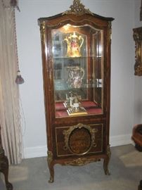 Large  ornate lighted curio cabinet with mirrored back and two glass shelves and beveled glass door and sides