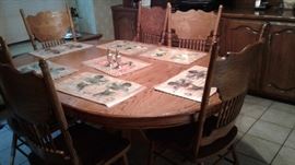 wooden dining table with 6 cushioned chairs, place mats, salt & pepper shakers