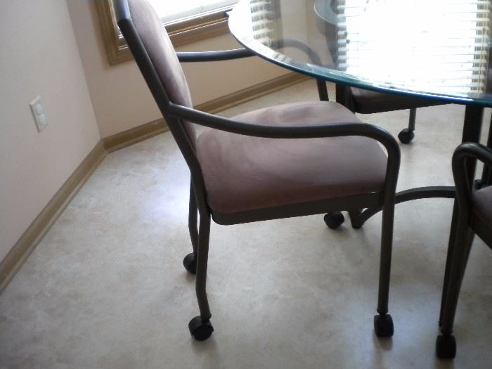 Kitchen table glass top with four armed chairs on casters