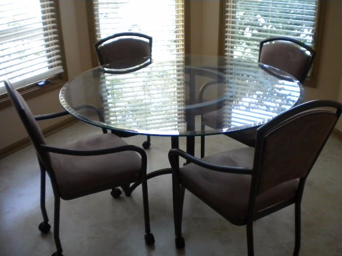 Kitchen table glass top with four armed chairs on casters