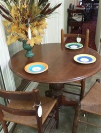 Round pedestal table, cane bottom chairs, plates made in Italy