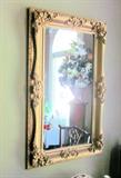 Mirror in ornate, wooden, antique frame; frame has been painted gold.