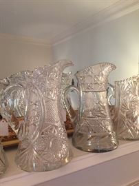 There are several antique cut glass pitchers