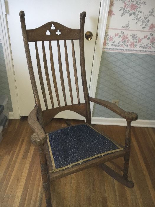 Antique oak rocking chair with shamrock cut-outs on back and carved rosettes on arms.