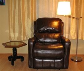 Oak Hexagon carved top Table with Glass Inset on a Black Pedestal Scroll Leg Base. Brown Leather Power Recliner and Chrome Adjustable Arm Floor Lamp