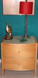 Palliser Furniture Mfg. Canada Mid-Century Style Natural Finish 2-drawer Night Stand with White Glass Top shown with 1 of a pair Chrome Spool Candlestick Lamps, a Silver Plastic Resin Couple with Child Sculpture and a sculptured Glass Pedestal Dresser Tray