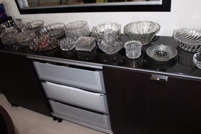 Huge amount of glass and crystal on a sideboard/buffet/chest with sliding doors and drawers.