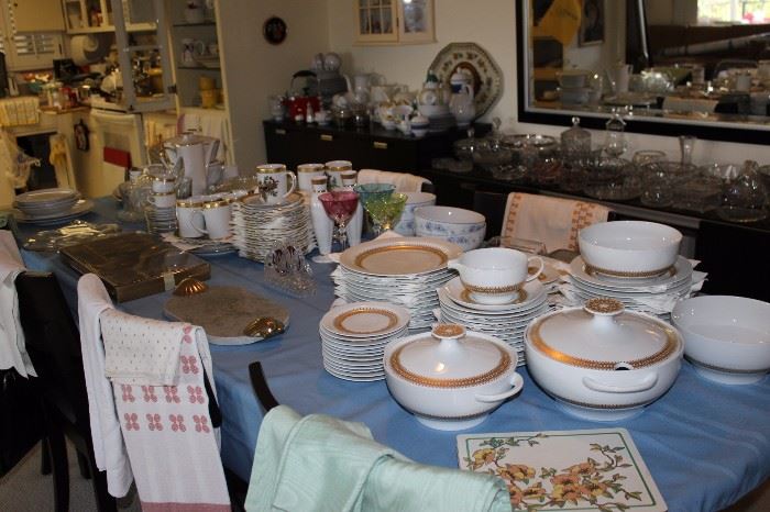 Tables covered inbone china dinner sets, serving pieces, table linens. large mirror, lots of clear glass and crystal pieces.