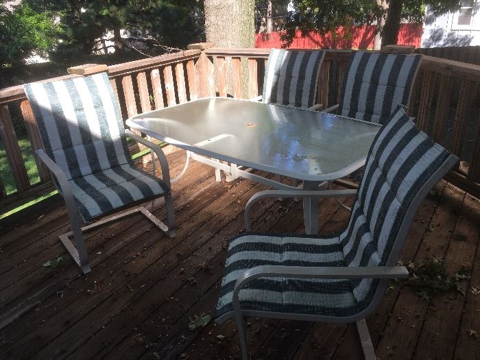 Glass top patio table with four striped chairs.