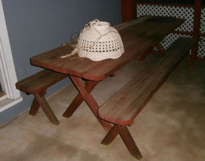 Long wooden picnic table and benches (1964) and hanging wicker lamp.