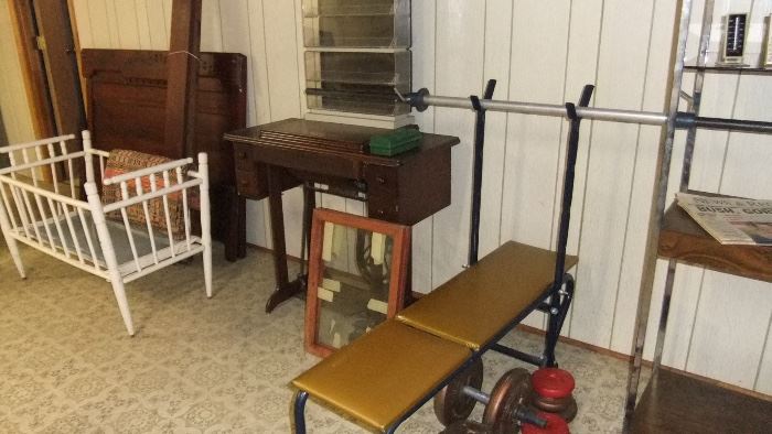 weight bench with bars and weights, antique white spindle crib, Eastlake full size bed, treadle Singer sewing machine in case